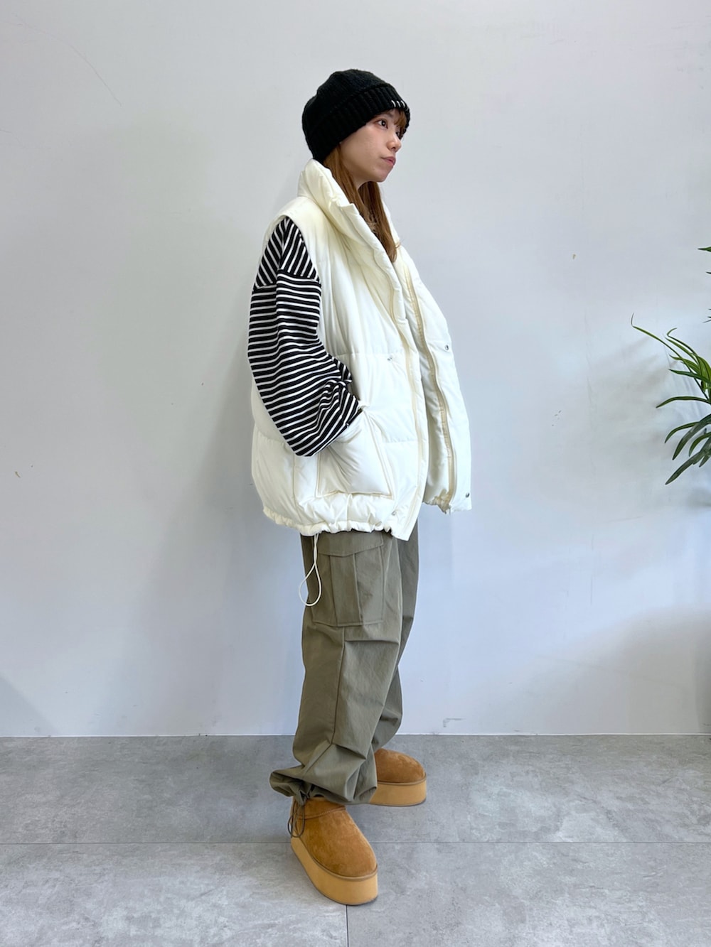 グリーン系のカーゴパンツ、ホワイト系のダウンベスト、ベージュ系のブーツを着用したレディースの冬コーディネートの5枚目の写真
