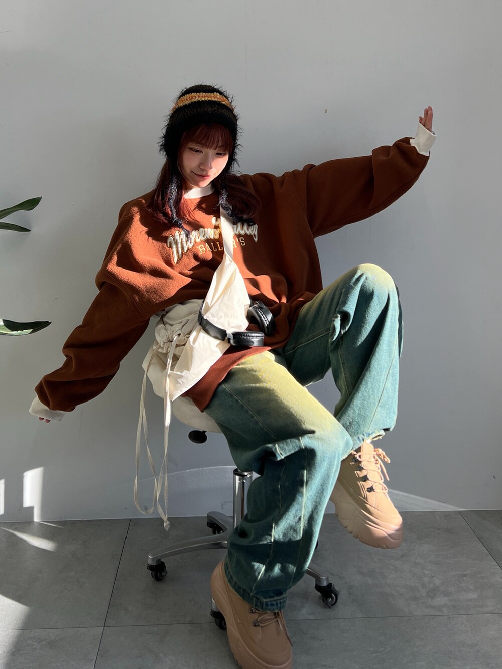 ブルー系のデニムパンツ、イエロー系のスニーカー、ホワイト系のショルダーバッグを着用したレディースの冬コーディネートの4枚目の写真