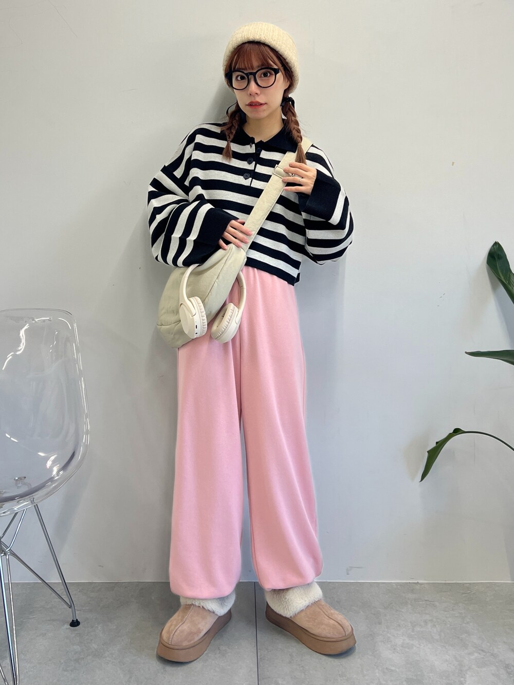 ピンク系のスウェットパンツ、ブラック系のニット/セーター、ホワイト系のショルダーバッグを着用したレディースの冬コーディネートの2枚目の写真