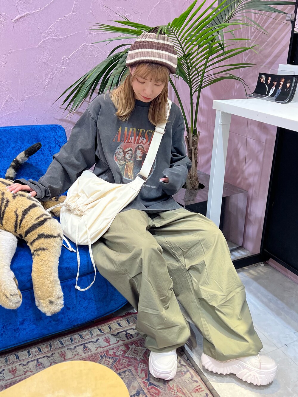 グリーン系のカーゴパンツ、ホワイト系のスニーカー、ホワイト系のショルダーバッグを着用したレディースの秋コーディネートの2枚目の写真