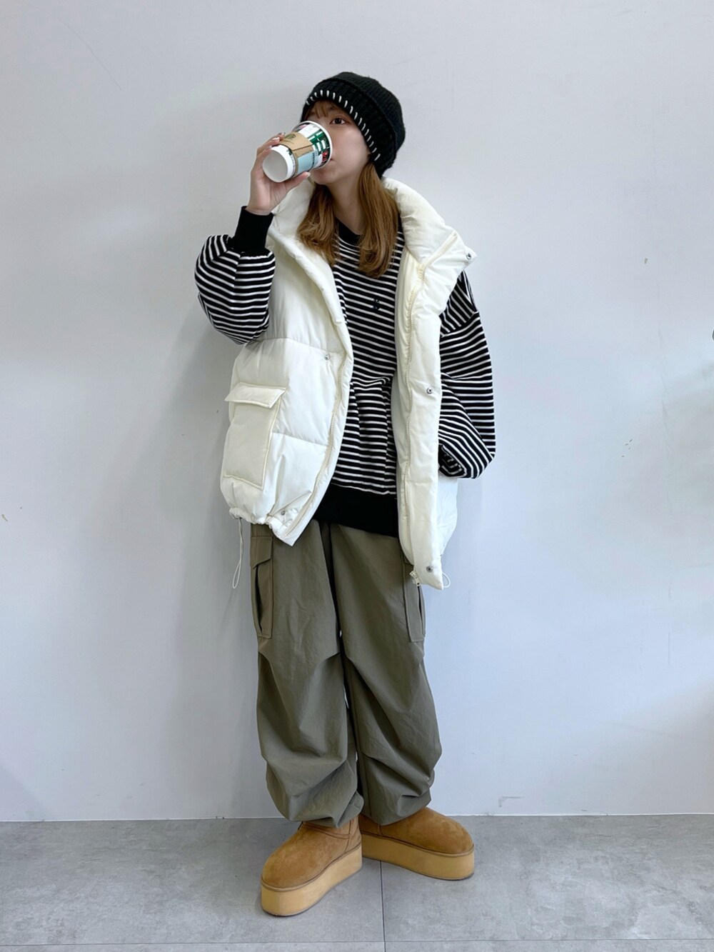 グリーン系のカーゴパンツ、ホワイト系のダウンベスト、ベージュ系のブーツを着用したレディースの冬コーディネートの4枚目の写真