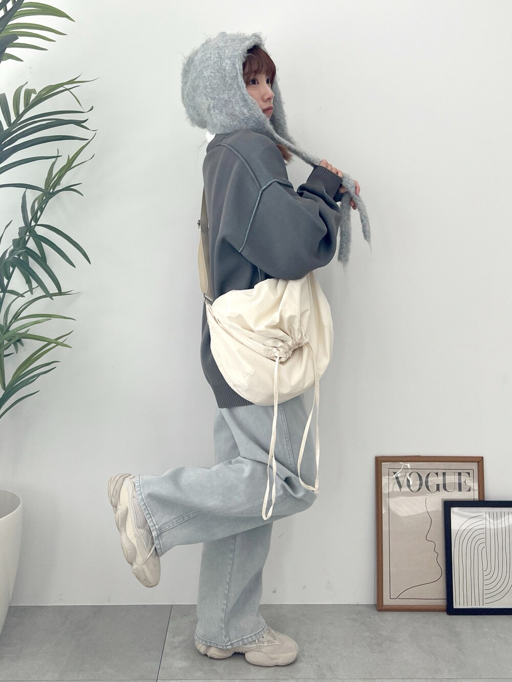 グレー系のカーディガン/ボレロ、グレー系のデニムパンツ、ホワイト系のショルダーバッグを着用したレディースの冬コーディネートの5枚目の写真