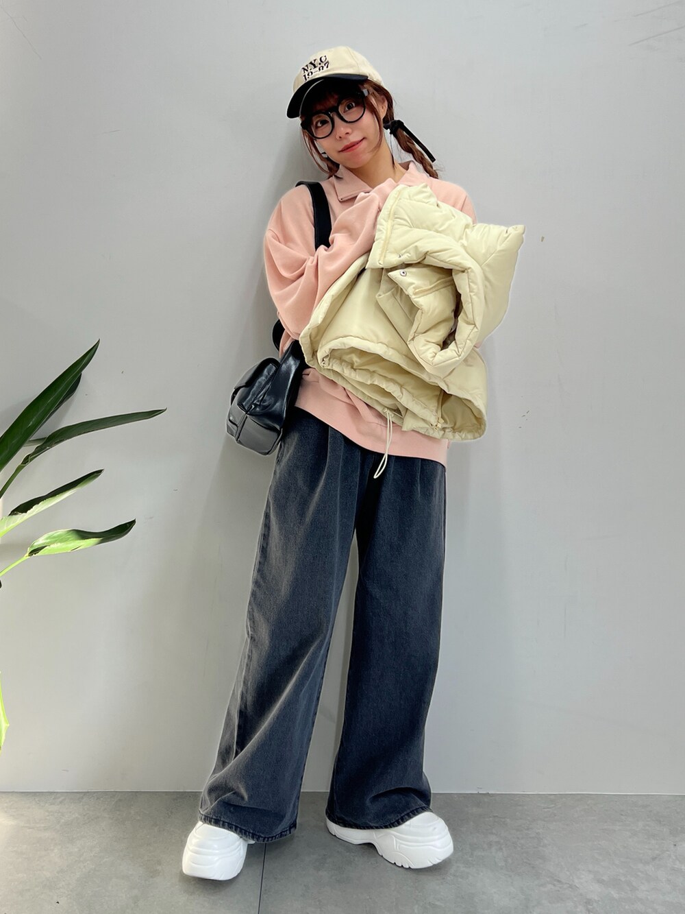 ブラック系のデニムパンツ、ピンク系のスウェット、ホワイト系のダウンベストを着用したレディースの冬コーディネートの3枚目の写真