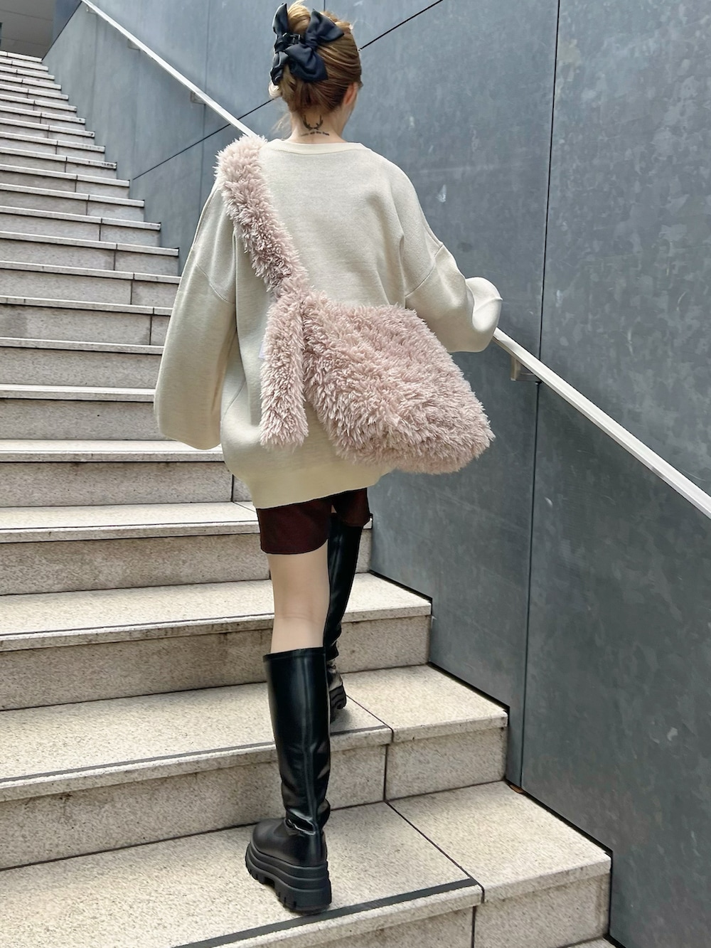 ホワイト系のニット/セーター、ブラウン系のスラックス、ブラック系のブーツを着用したレディースの秋コーディネートの2枚目の写真