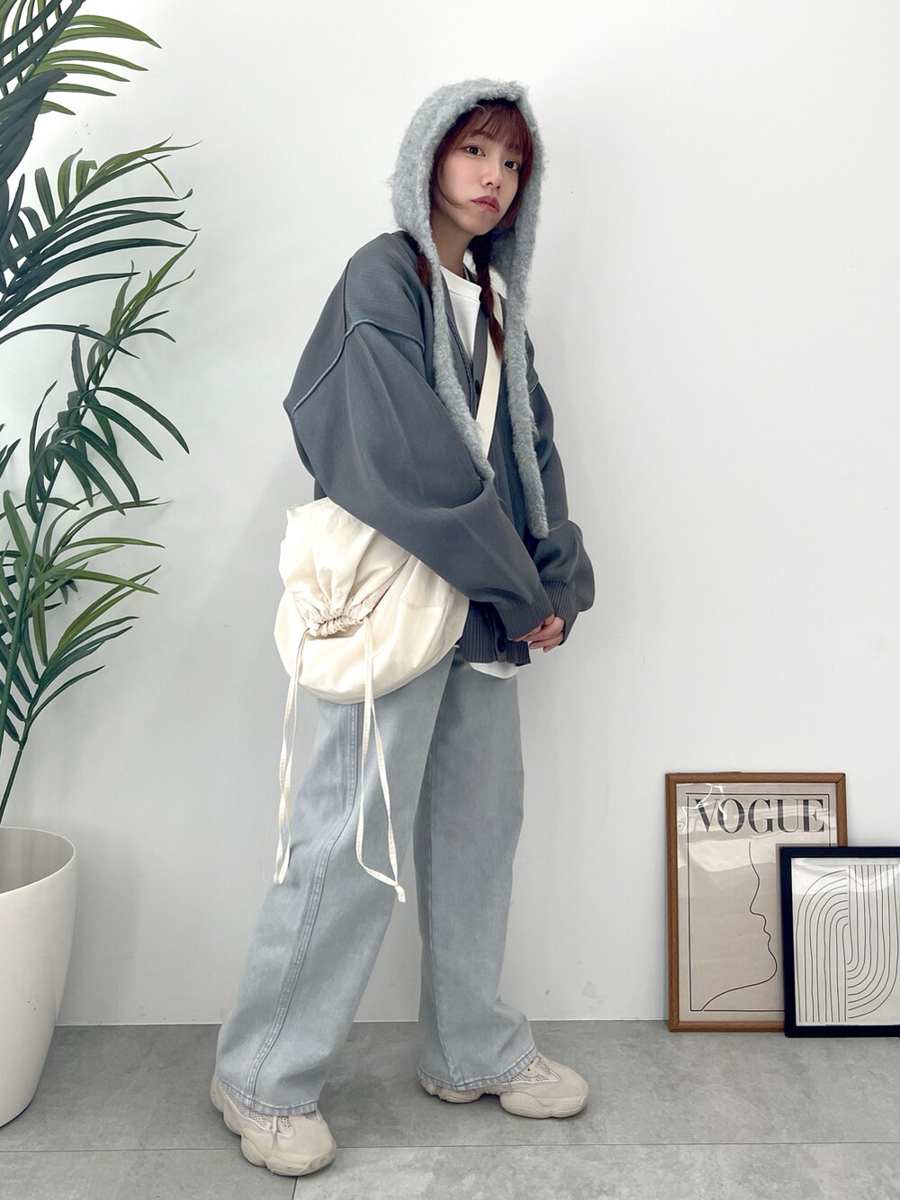 グレー系のカーディガン/ボレロ、グレー系のデニムパンツ、ホワイト系のショルダーバッグを着用したレディースの冬コーディネートの2枚目の写真