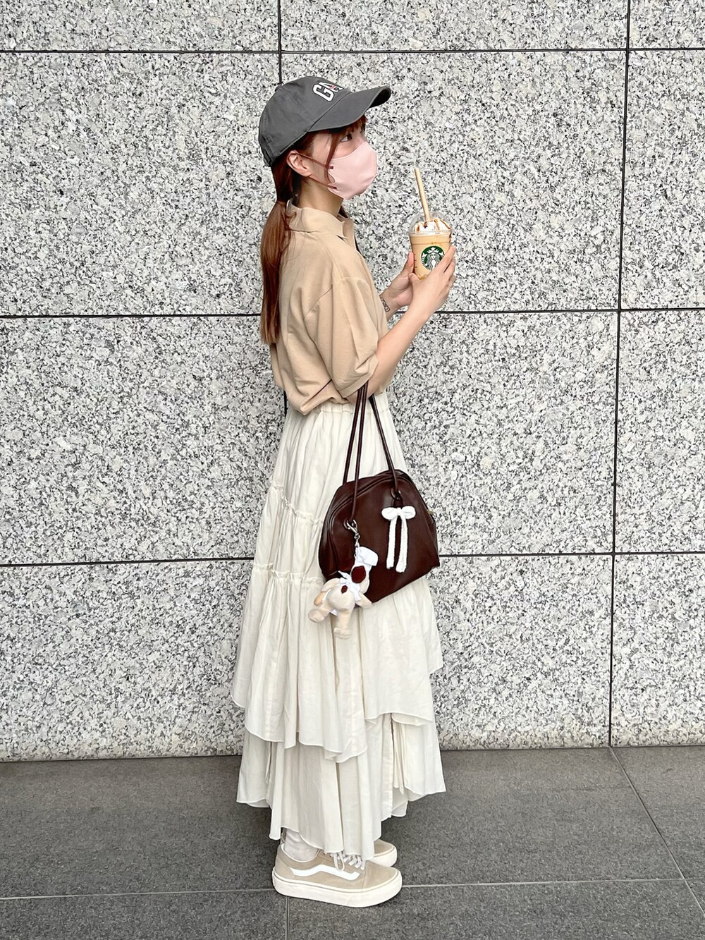 ベージュ系のポロシャツ、ホワイト系のスカート、ベージュ系のスニーカーを着用したレディースの夏コーディネートの2枚目の写真