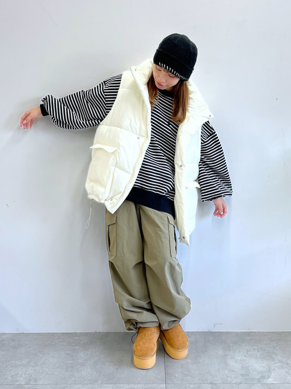 グリーン系のカーゴパンツ、ホワイト系のダウンベスト、ベージュ系のブーツを着用したレディースの冬コーディネートの2枚目の写真