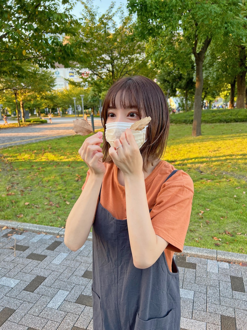 オレンジ系のスニーカー、オレンジ系のTシャツ/カットソー、グレー系のサロペット/オーバーオールを着用したレディースの秋コーディネートの2枚目の写真