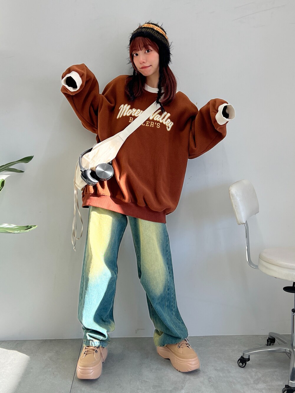 ブルー系のデニムパンツ、イエロー系のスニーカー、ホワイト系のショルダーバッグを着用したレディースの冬コーディネートの3枚目の写真