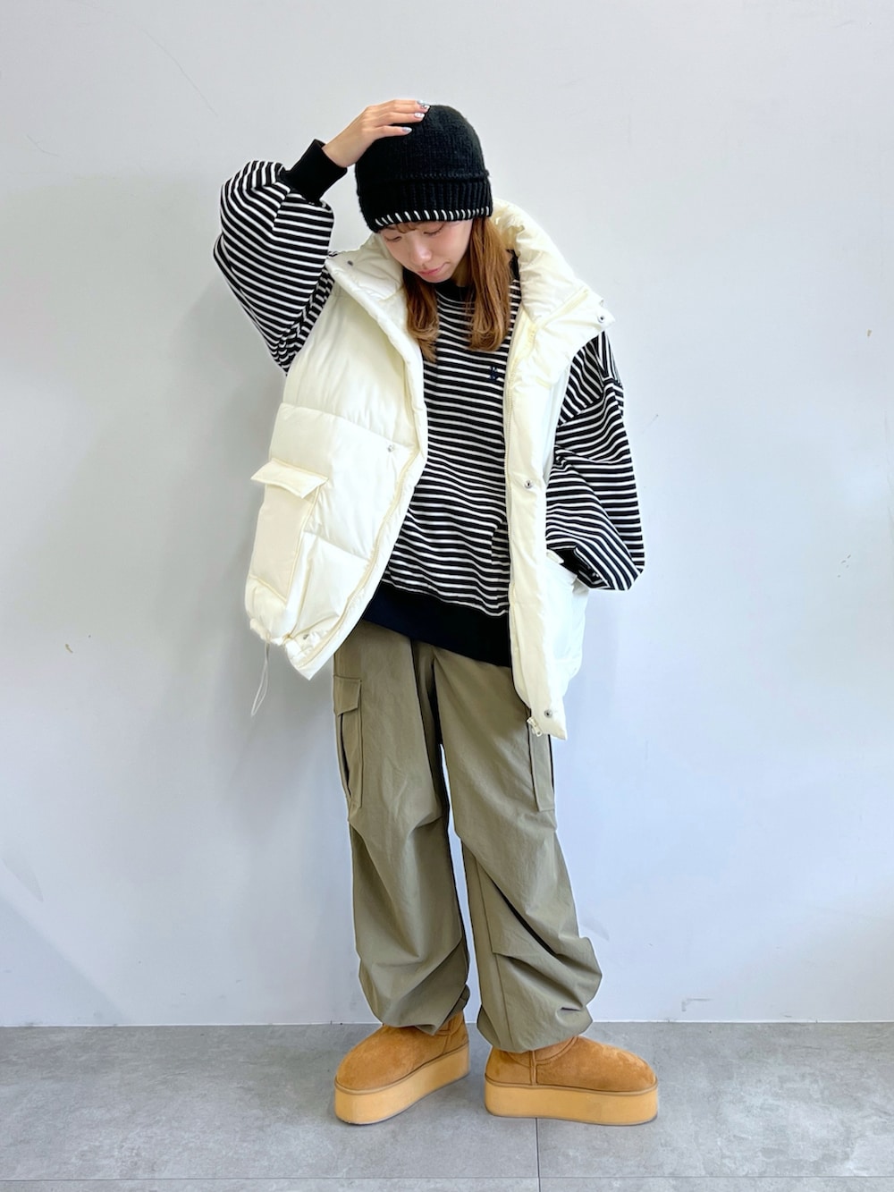 グリーン系のカーゴパンツ、ホワイト系のダウンベスト、ベージュ系のブーツを着用したレディースの冬コーディネートの3枚目の写真
