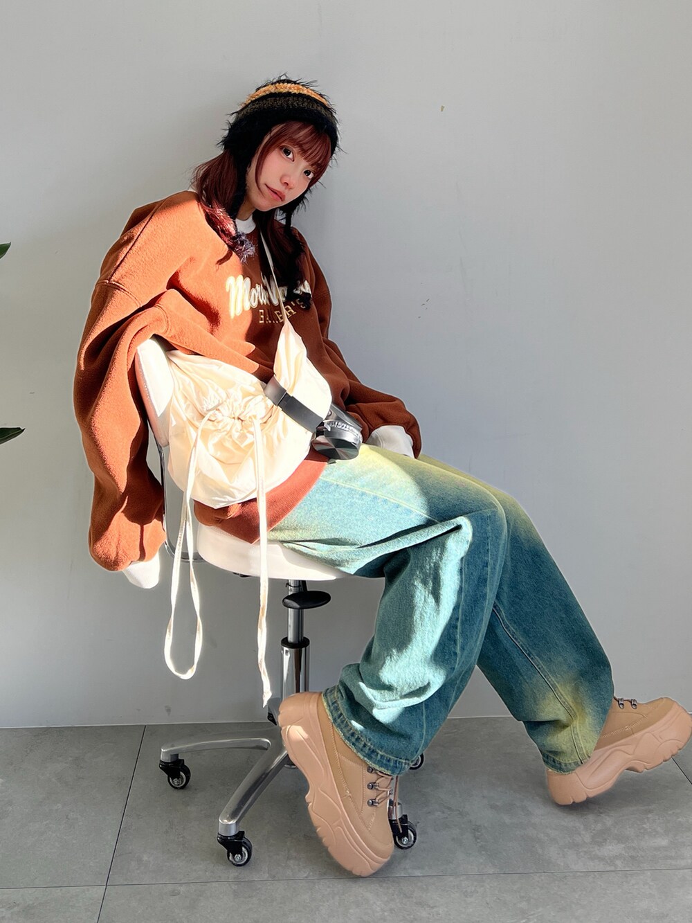 ブルー系のデニムパンツ、イエロー系のスニーカー、ホワイト系のショルダーバッグを着用したレディースの冬コーディネートの5枚目の写真