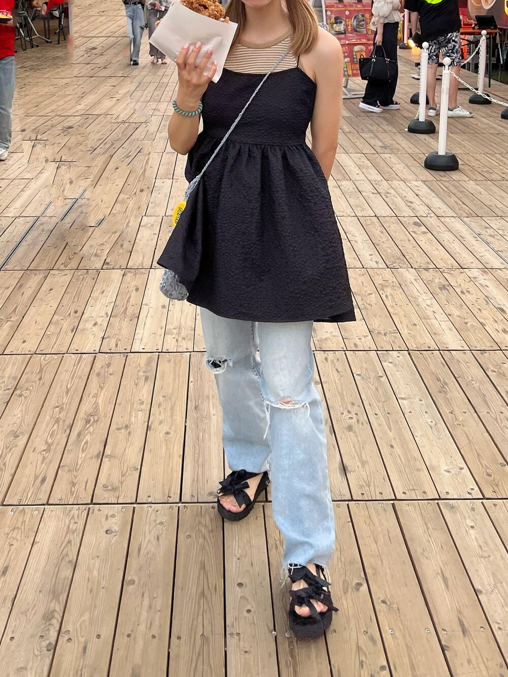 ブルー系のデニムパンツ、ブラック系のサンダル、ブラック系のワンピースを着用したレディースの秋コーディネートの3枚目の写真