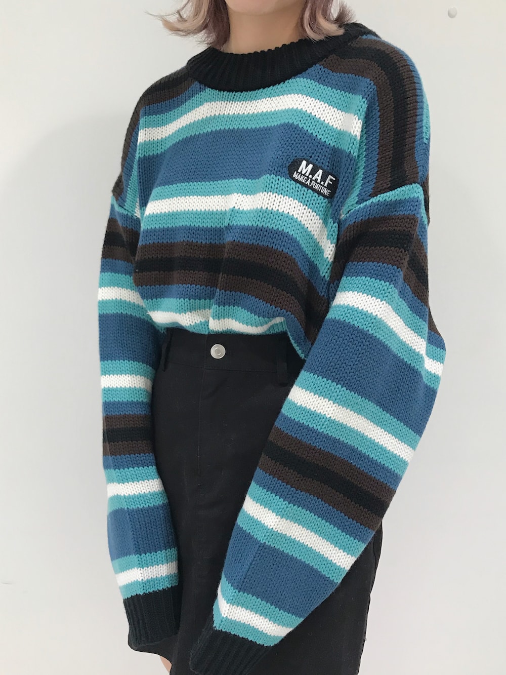 ブラック系のスカート、ベージュ系のスニーカー、ブルー系のニット/セーターを着用したレディースの秋コーディネートの2枚目の写真