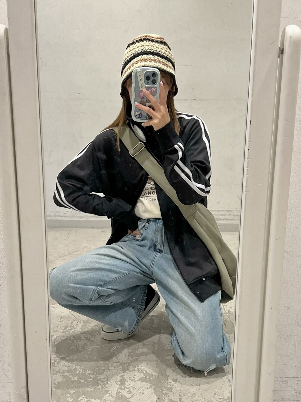 ブラック系のスニーカー、ブルー系のデニムパンツ、グリーン系のショルダーバッグを着用したレディースの夏コーディネートの2枚目の写真