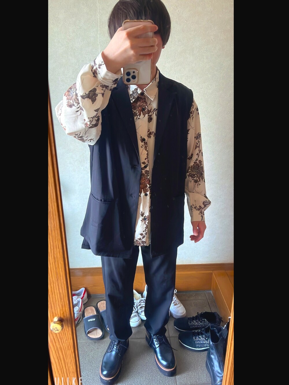 ブラック系のベスト、ブラック系のスラックス、ブラウン系のドレスシューズを着用したメンズの春コーディネートの2枚目の写真