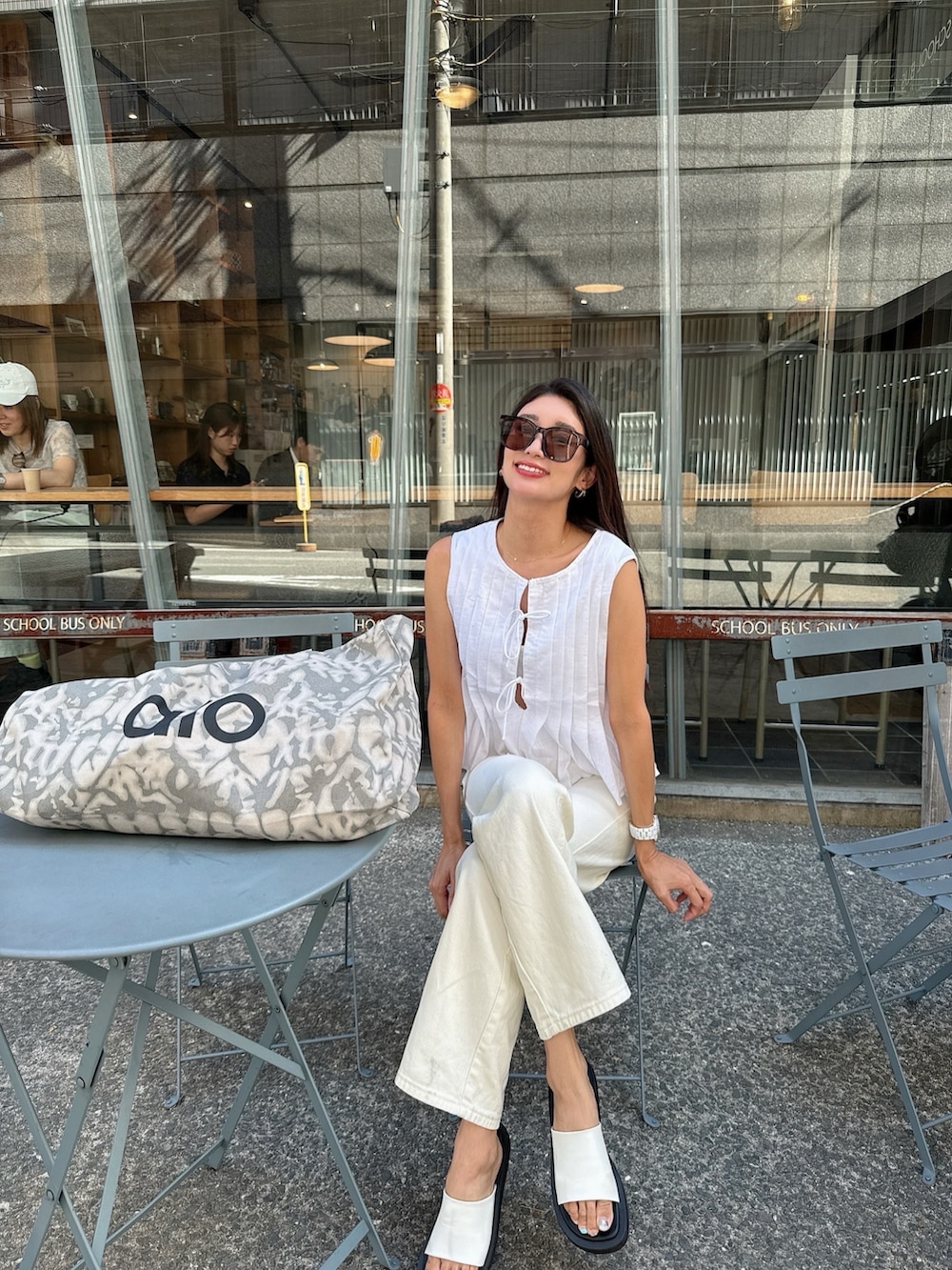シルバー系のトートバッグ、ホワイト系のスリッポン、ホワイト系のパンツを着用したレディースの夏コーディネートの2枚目の写真