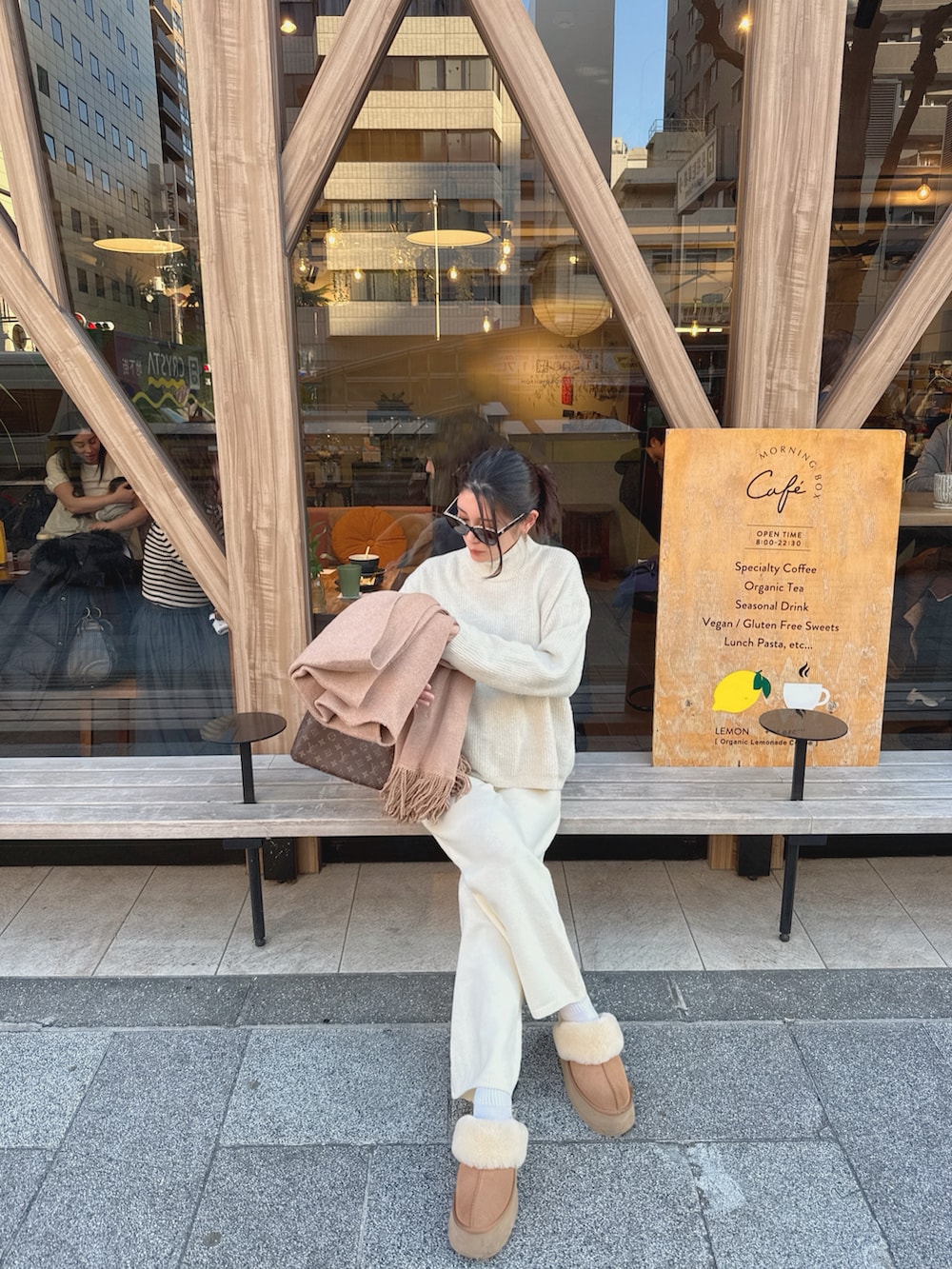 ホワイト系のニット/セーター、ブラウン系のハンドバッグ、ベージュ系のスリッポンを着用したレディースの冬コーディネートの2枚目の写真