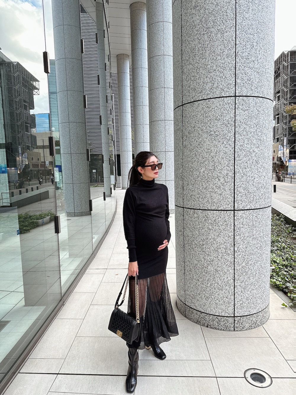 ブラック系のワンピース、ブラック系のハンドバッグ、ブラック系のブーツを着用したレディースの秋コーディネートの2枚目の写真