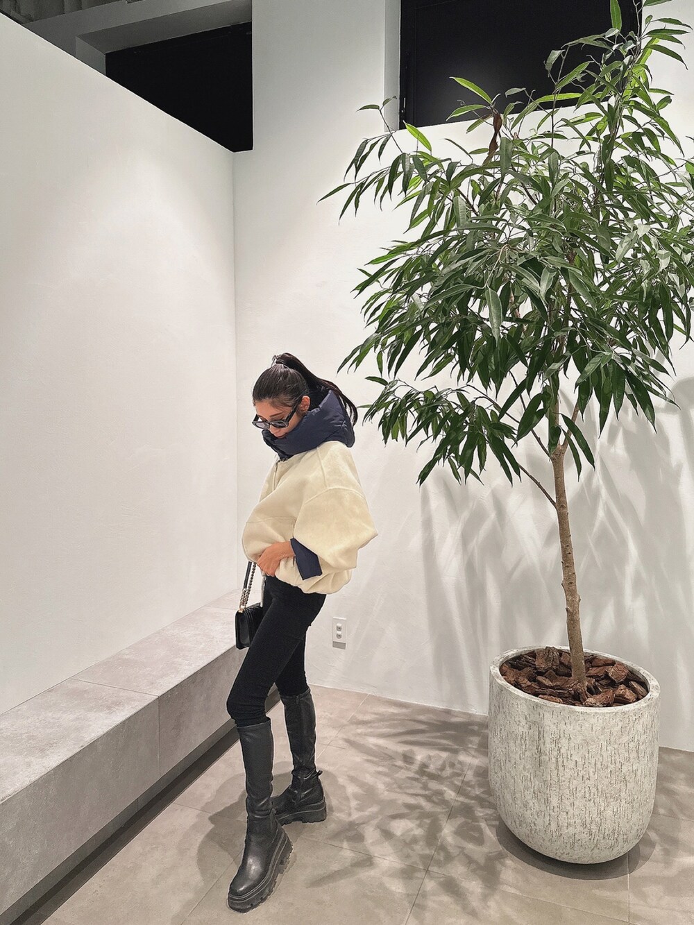 ホワイト系のダウンジャケット/コート、ブラック系のブーツ、ブラック系のハンドバッグを着用したレディースの冬コーディネートの2枚目の写真