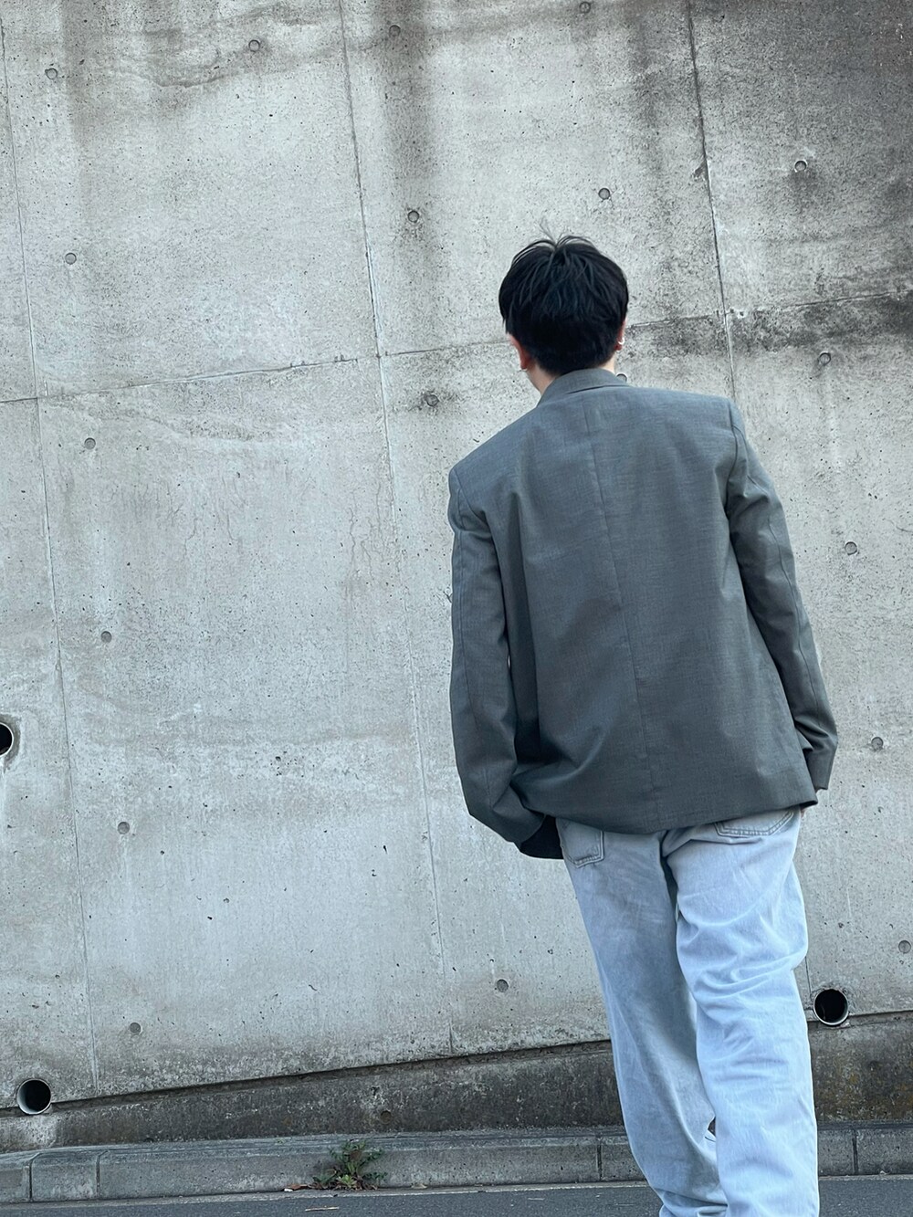 グレー系のテーラードジャケット、ブルー系のデニムパンツ、ブラック系のローファーを着用したメンズの春コーディネートの2枚目の写真