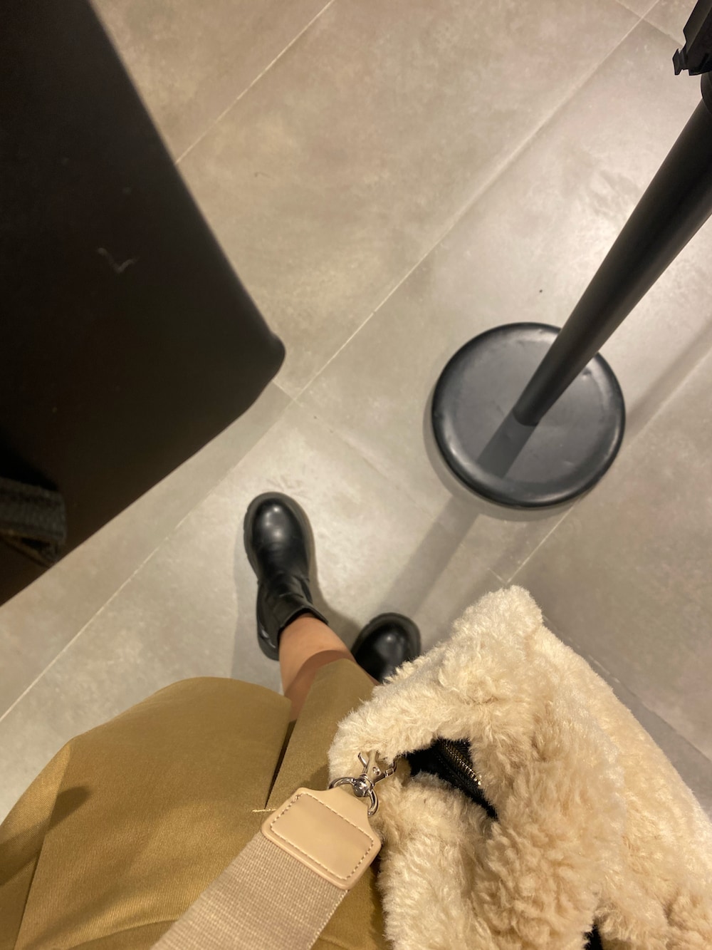 ホワイト系のTシャツ/カットソー、ベージュ系のスカート、ブラック系のブーツを着用したレディースの秋コーディネートの2枚目の写真