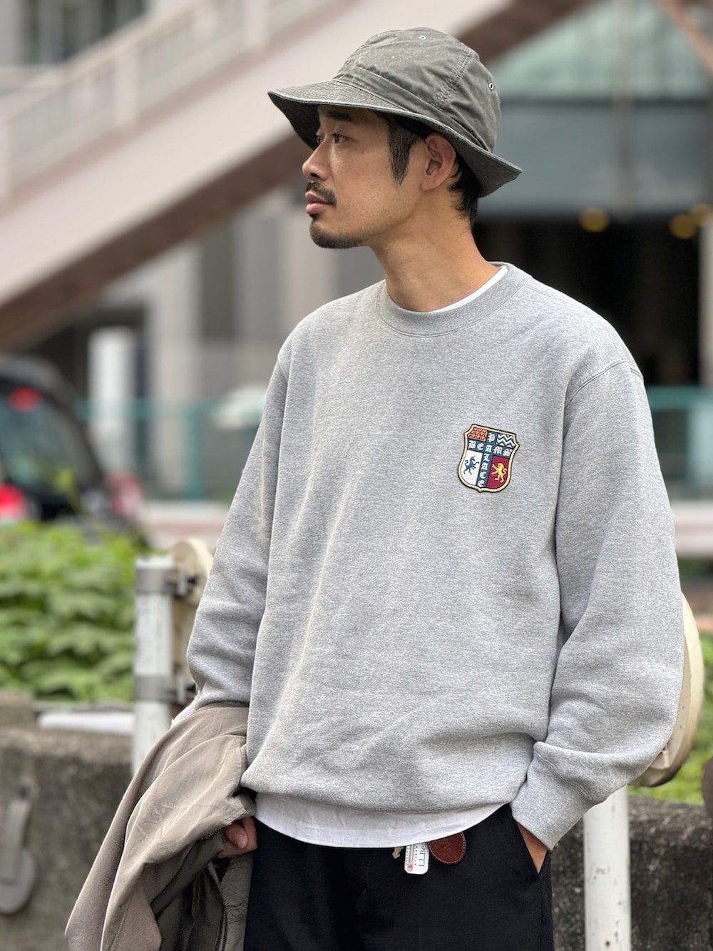 ブルー系のスラックス、ブルー系のスニーカー、グリーン系のハットを着用したメンズの秋コーディネートの3枚目の写真