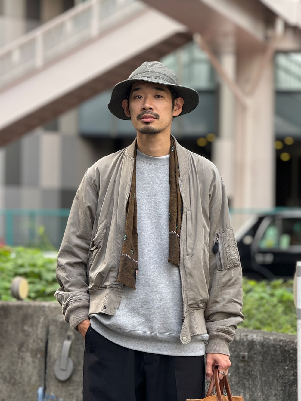 ブルー系のスラックス、ブルー系のスニーカー、グリーン系のハットを着用したメンズの秋コーディネートの2枚目の写真