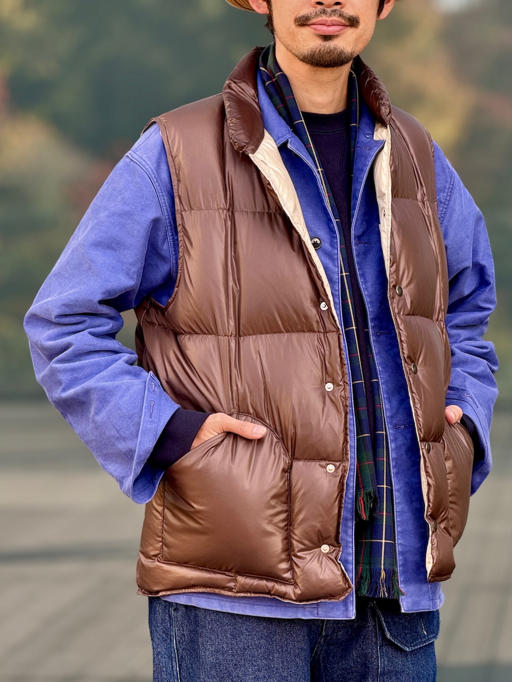 ブラウン系のダウンベスト、パープル系のブルゾン、ブラウン系のハットを着用したメンズの冬コーディネートの2枚目の写真