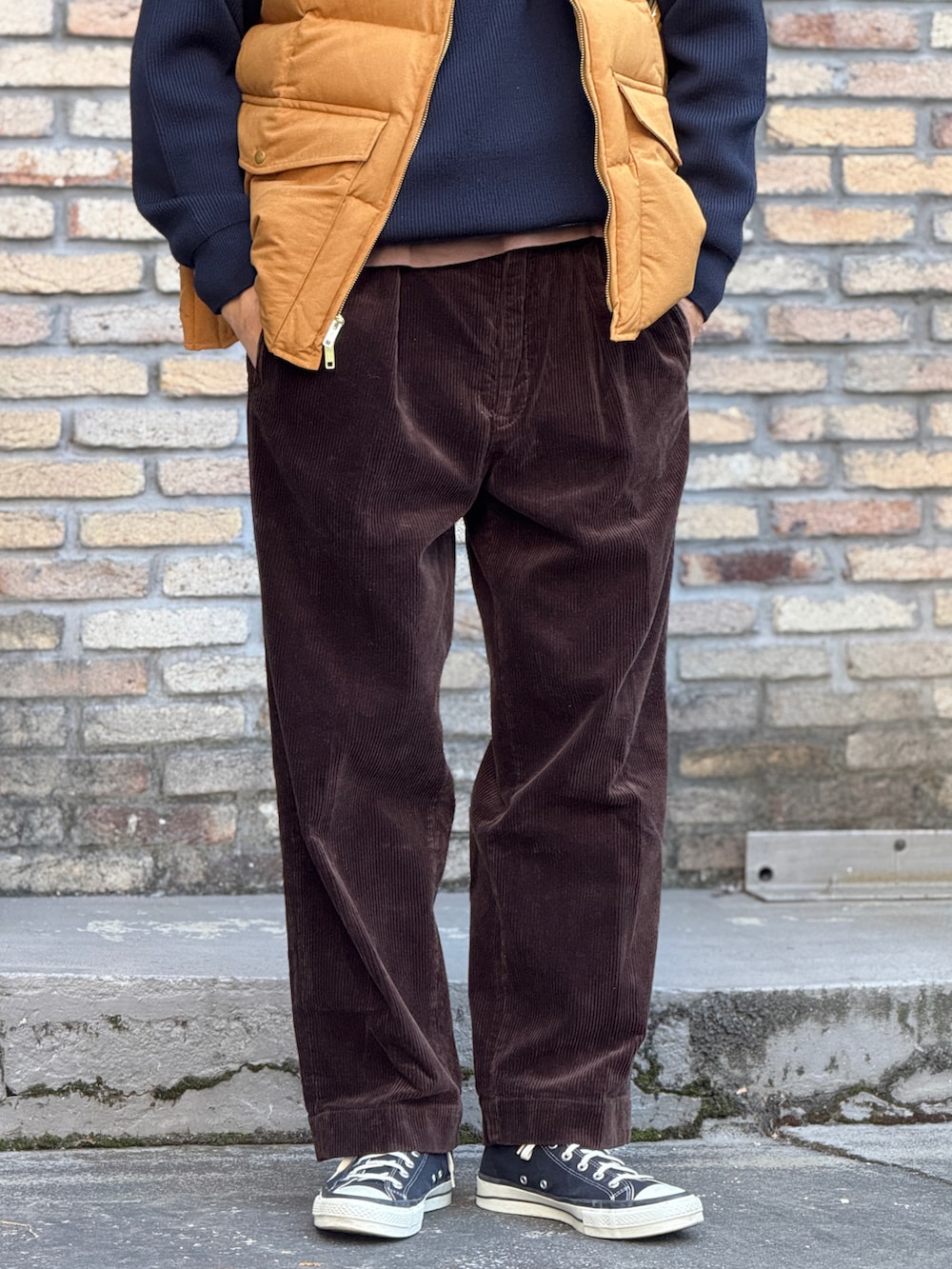 ゴールド系のダウンベスト、ブラウン系のトートバッグ、その他のハットを着用したメンズの冬コーディネートの4枚目の写真