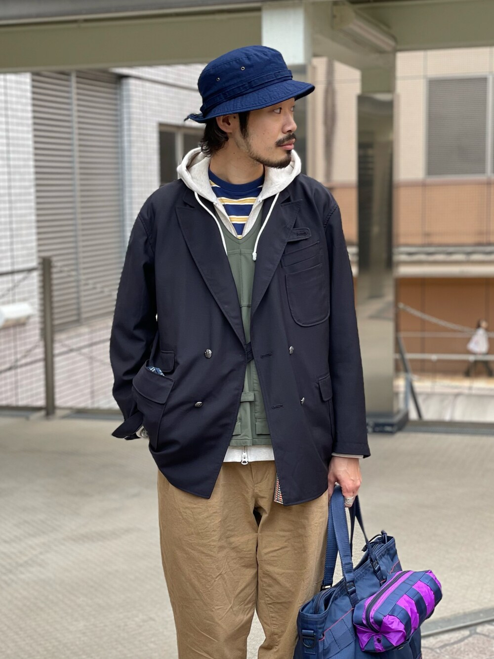 ブラウン系のチノパンツ、ベージュ系のスウェット、ブルー系のキャップを着用したメンズの春コーディネートの2枚目の写真