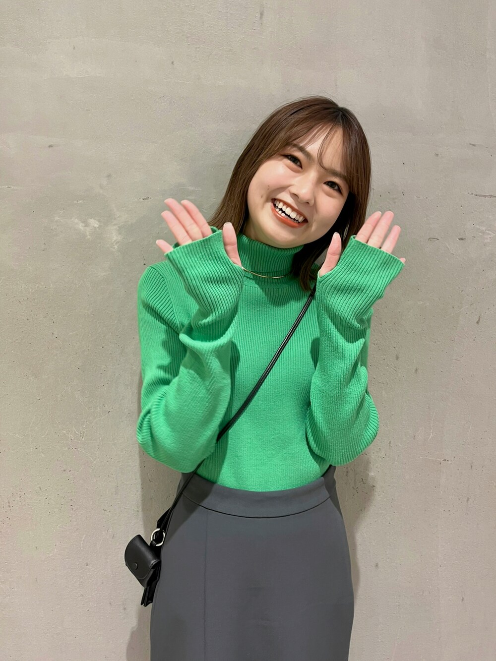 グリーン系のニット/セーター、グレー系のスカート、ブラック系のブーツを着用したレディースの冬コーディネートの3枚目の写真