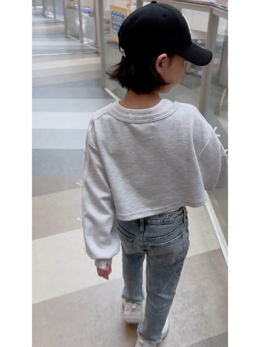グレー系のスウェット、ブルー系のデニムパンツ、ブラック系のキャップを着用したレディースの春コーディネートの2枚目の写真
