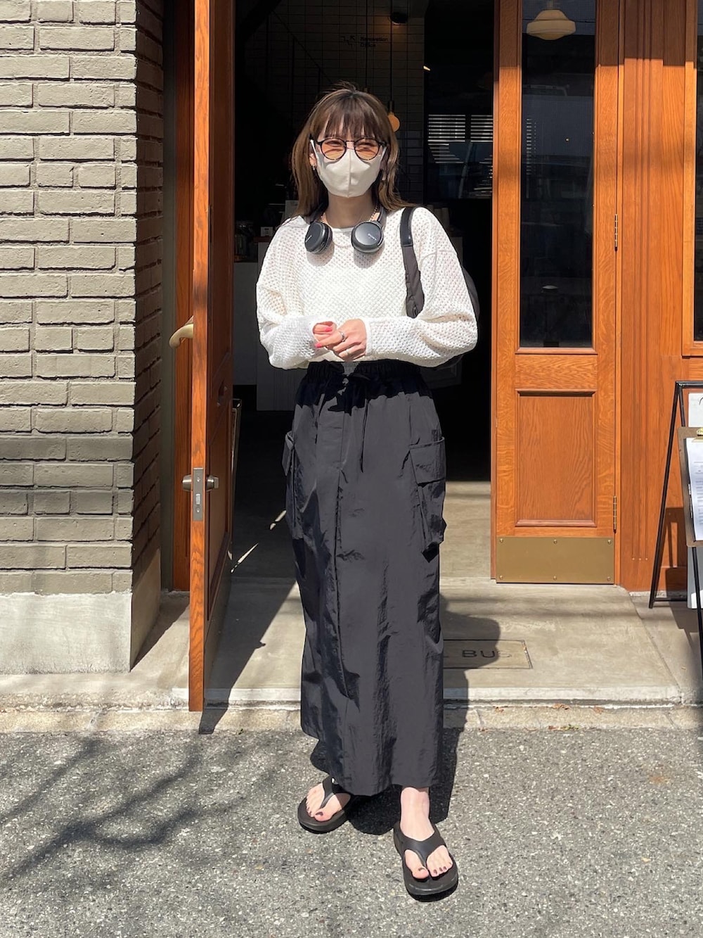 ホワイト系のニット/セーター、ブラック系のスカート、ブラック系のハンドバッグを着用したレディースの春コーディネートの2枚目の写真