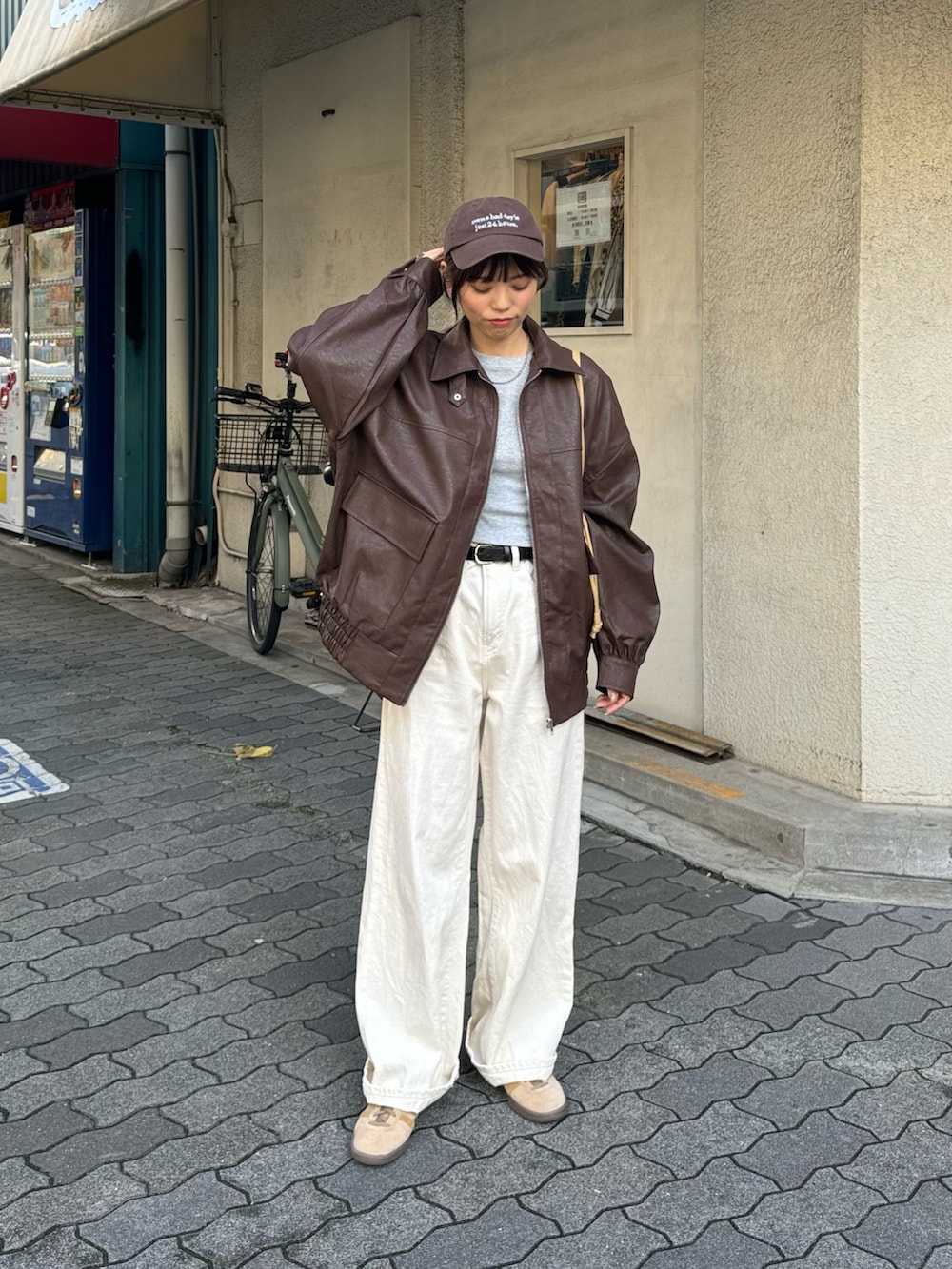 ブラウン系のブルゾン、ホワイト系のデニムパンツ、ベージュ系のスニーカーを着用したレディースの秋コーディネートの3枚目の写真
