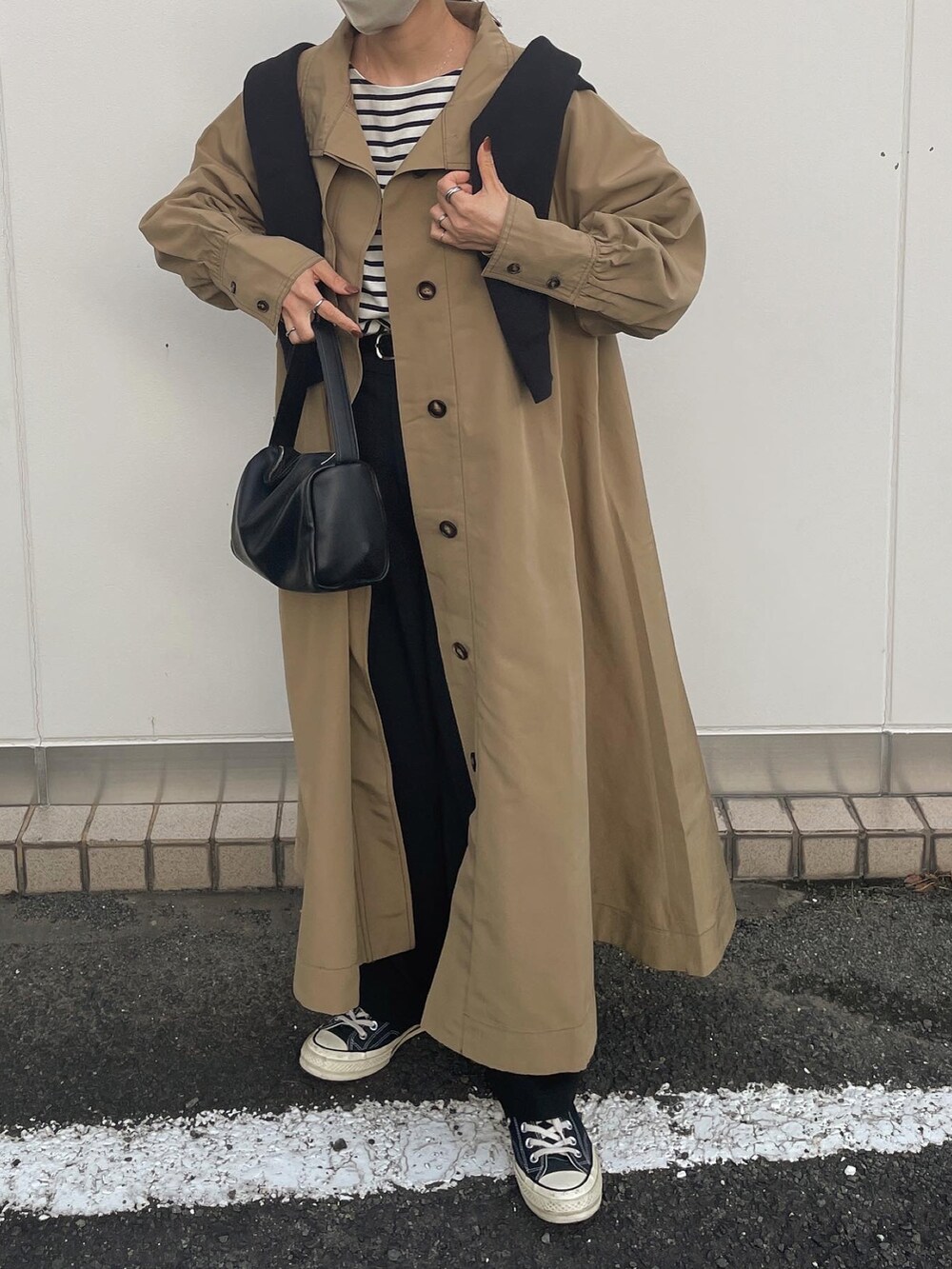 ベージュ系のトレンチコートを着用したレディースの秋コーディネートの2枚目の写真