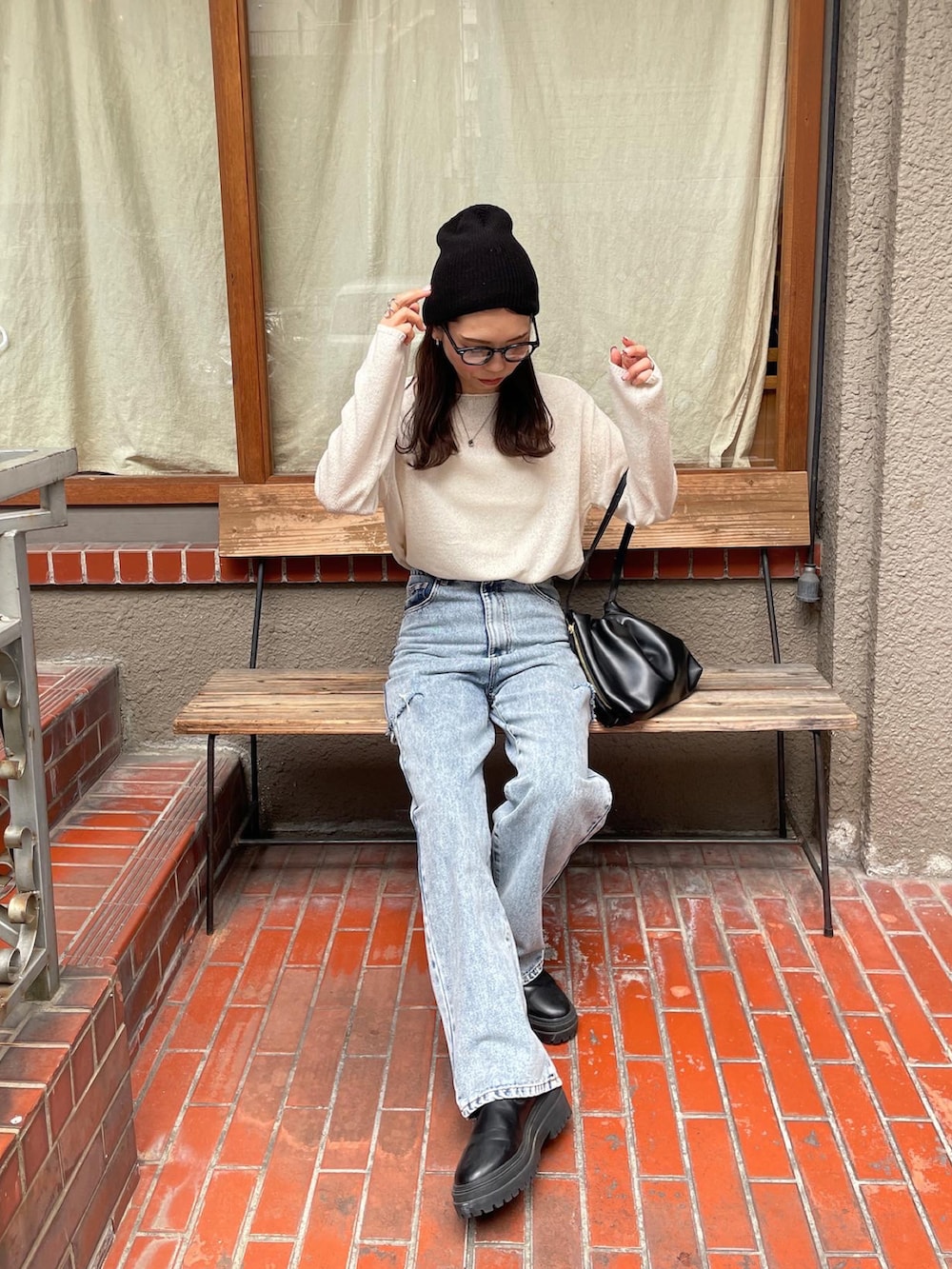 ホワイト系のニット/セーター、ブルー系のデニムパンツ、ブラック系のショルダーバッグを着用したレディースの夏コーディネートの2枚目の写真