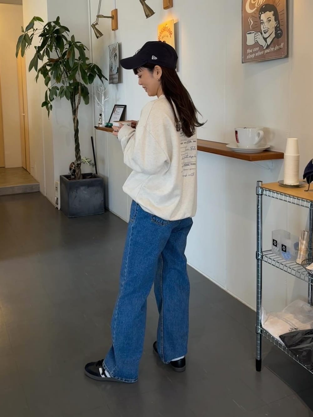 ホワイト系のスウェット、ブルー系のデニムパンツ、ブラック系のスニーカーを着用したレディースの春コーディネートの2枚目の写真