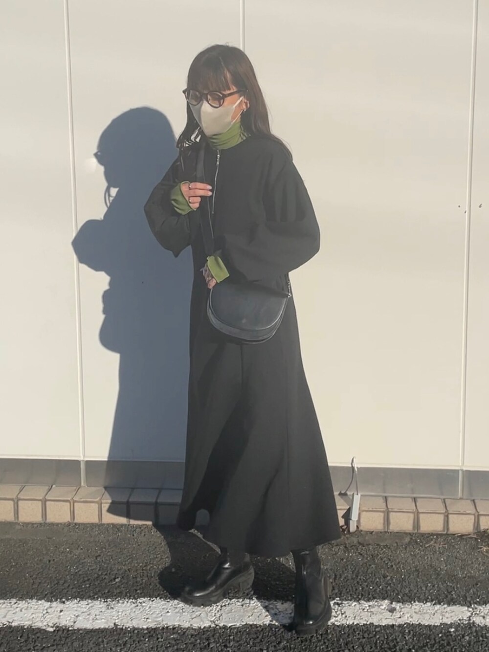 ブラック系のワンピース、ブラック系のショルダーバッグ、グリーン系のTシャツ/カットソーを着用したレディースの冬コーディネートの3枚目の写真