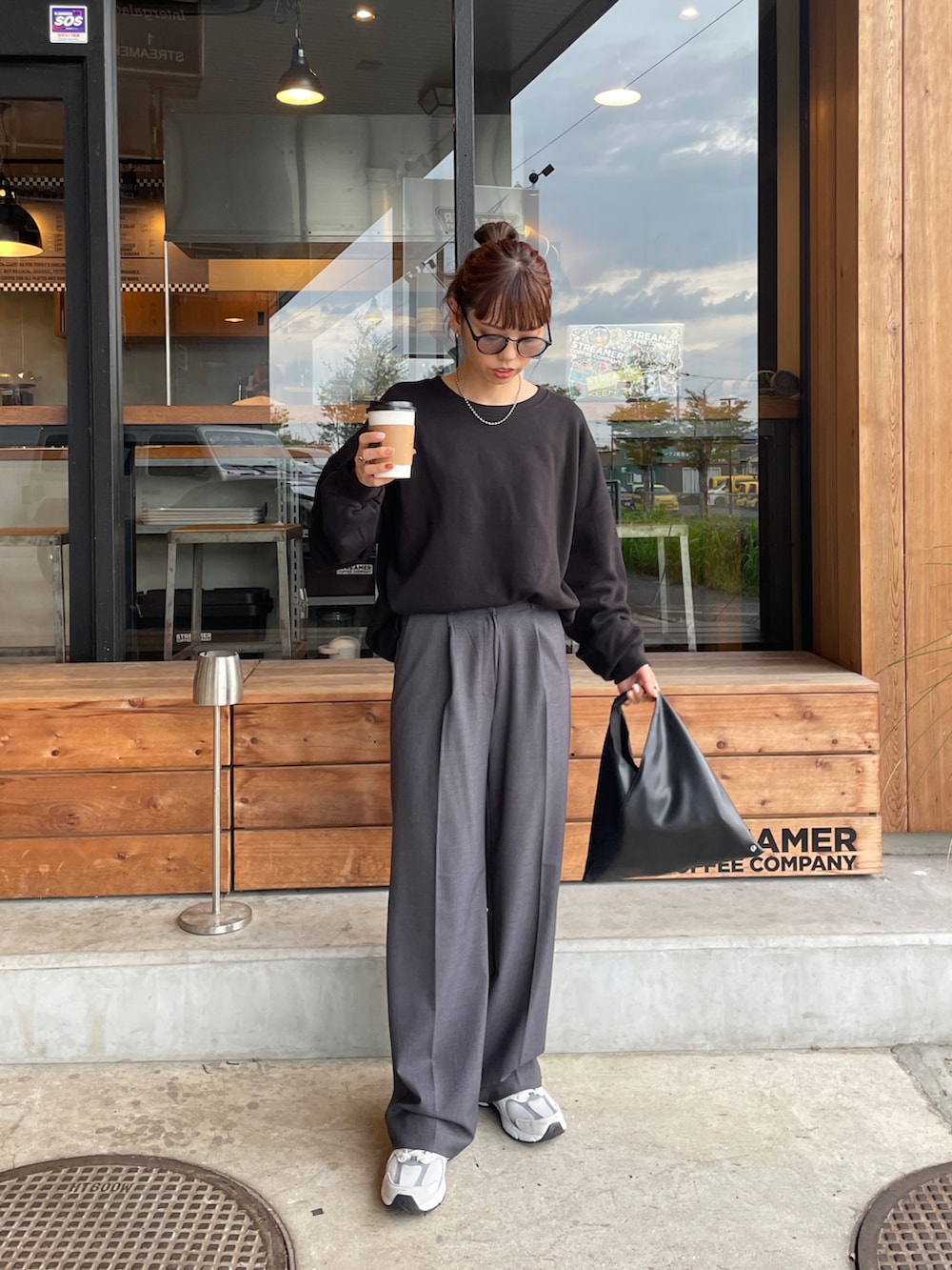 ブラック系のスウェット、ブラック系のトートバッグ、ホワイト系のスニーカーを着用したレディースの秋コーディネートの3枚目の写真