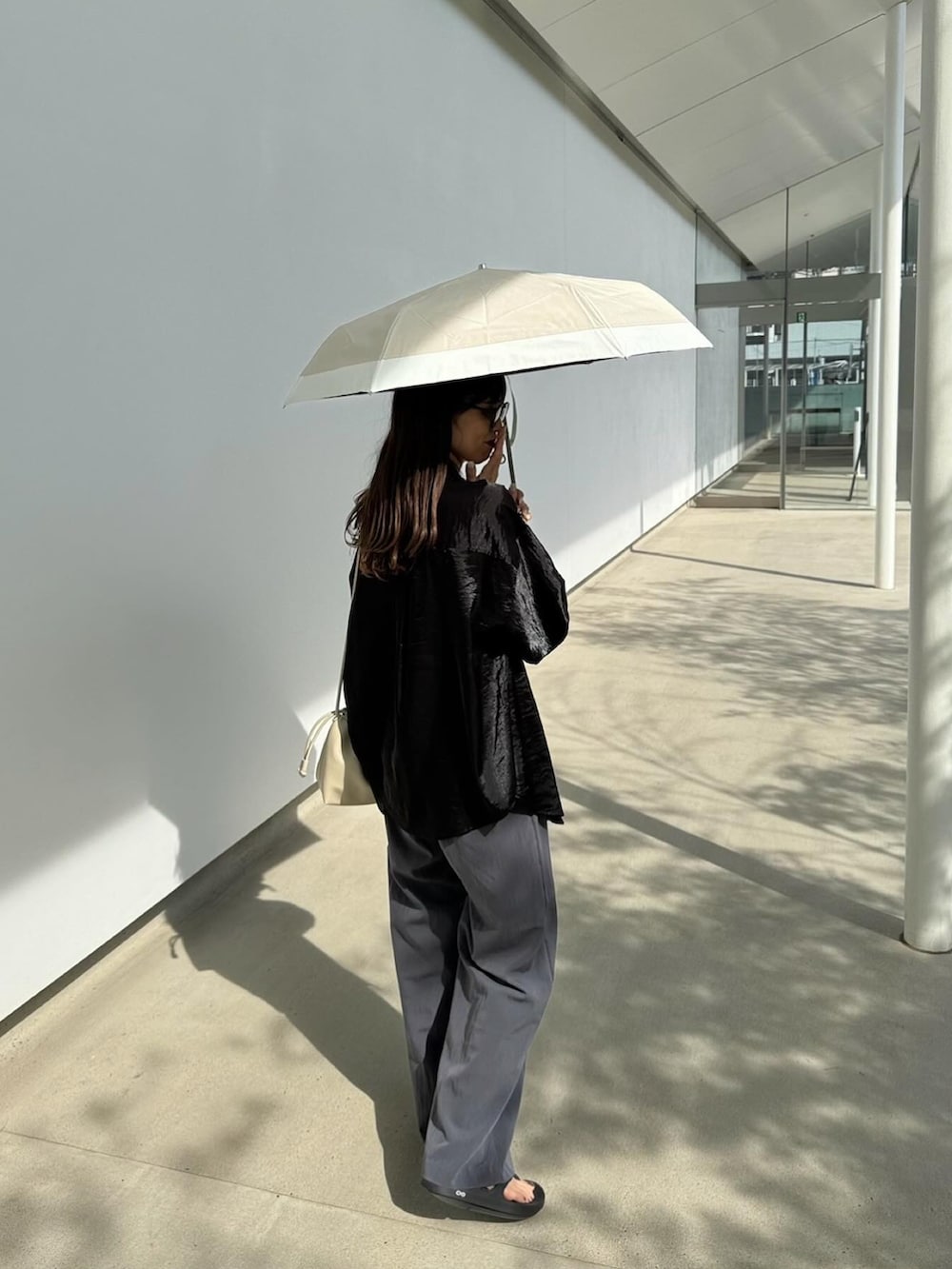 ホワイト系のショルダーバッグ、ベージュ系の折りたたみ傘を着用したレディースの春コーディネートの4枚目の写真