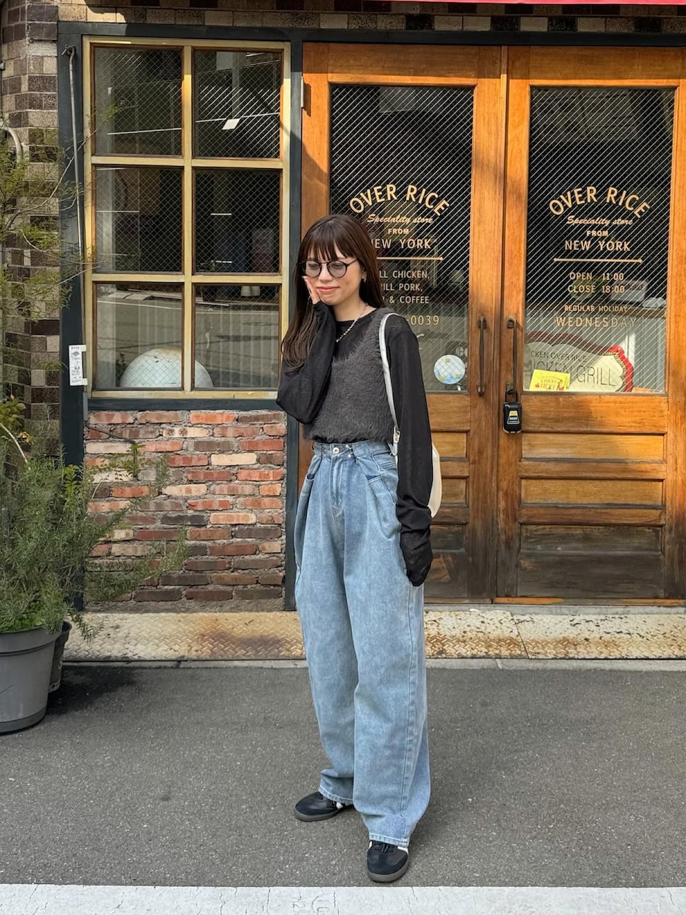 ブルー系のデニムパンツ、ホワイト系のショルダーバッグ、ブラック系のスニーカーを着用したレディースの冬コーディネートの2枚目の写真