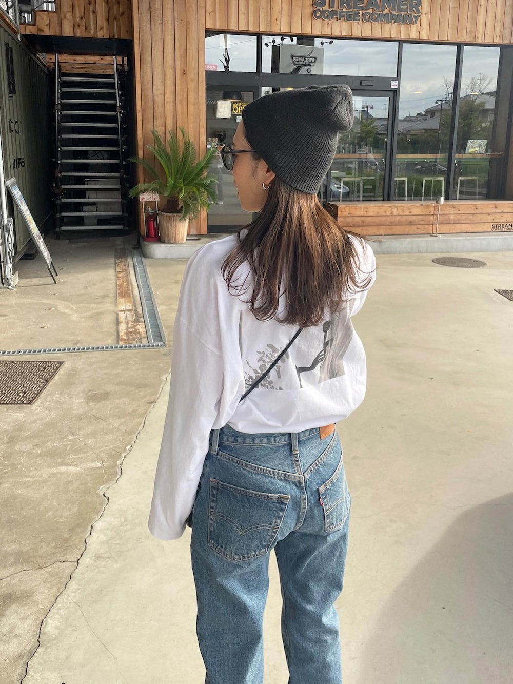 ホワイト系のTシャツ/カットソー、ブルー系のデニムパンツ、ホワイト系のスニーカーを着用したレディースの秋コーディネートの3枚目の写真