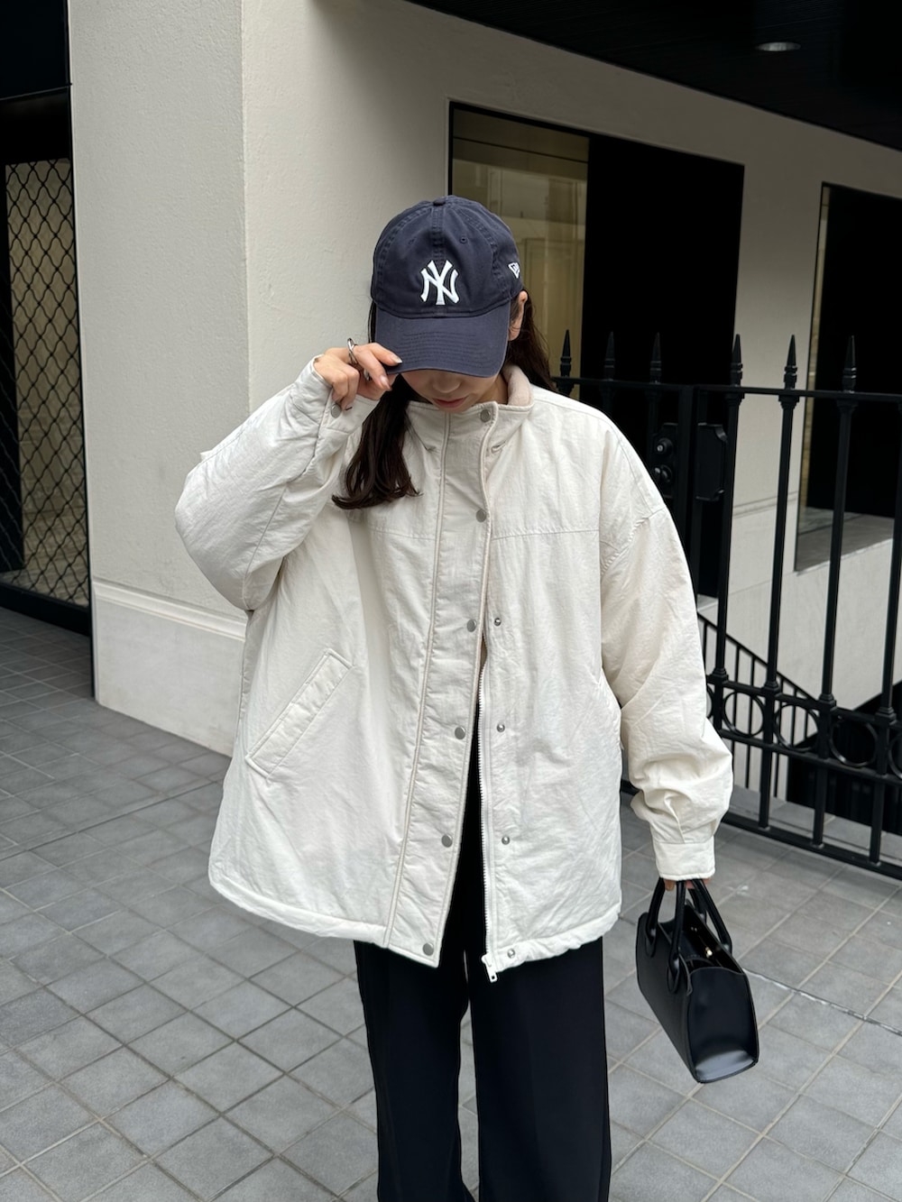 ホワイト系のブルゾン、ブラック系のスラックスを着用したレディースの秋コーディネートの3枚目の写真