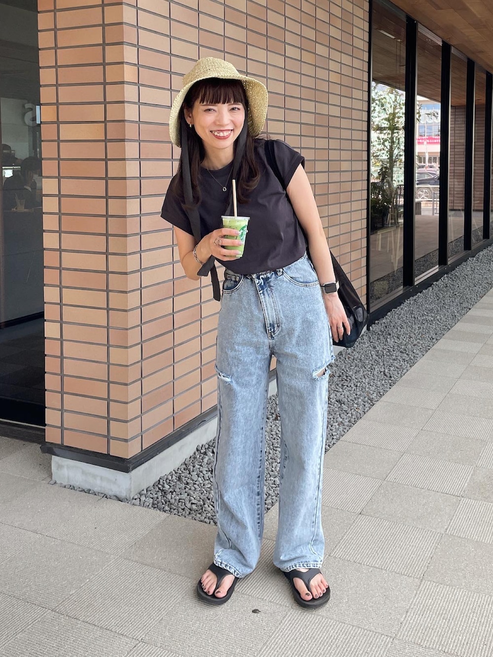 ブルー系のデニムパンツ、ブラック系のトートバッグ、ベージュ系のハットを着用したレディースの夏コーディネートの3枚目の写真