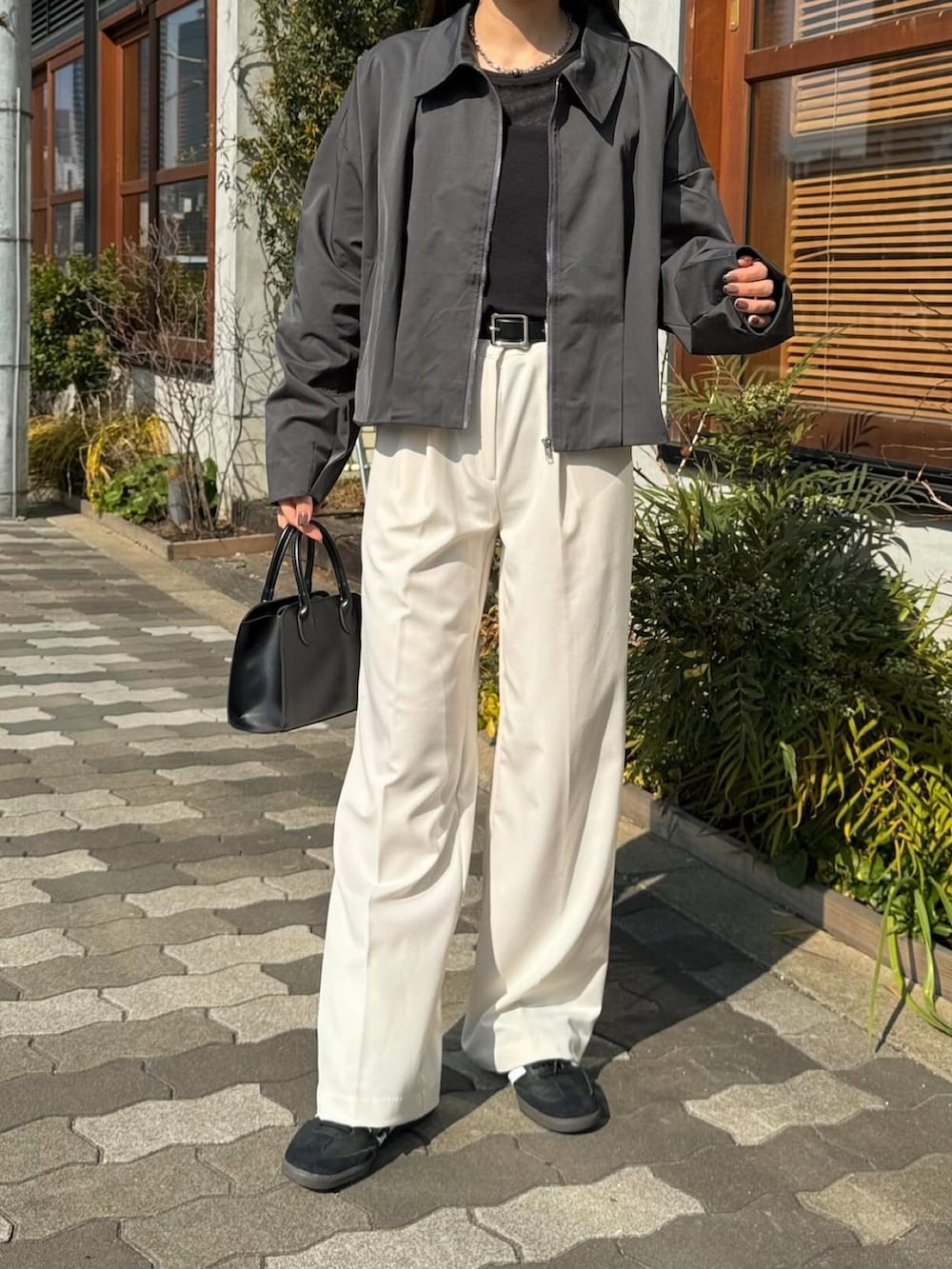 グレー系のブルゾン、ブラック系のTシャツ/カットソー、ホワイト系のスラックスを着用したレディースの春コーディネートの3枚目の写真
