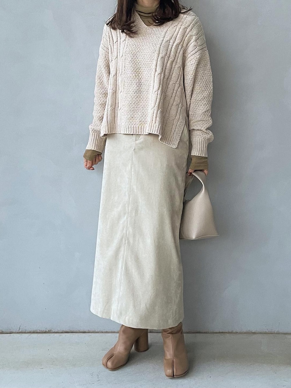 ホワイト系のニット/セーター、ホワイト系のスカート、グリーン系のTシャツ/カットソーを着用したレディースの冬コーディネートの2枚目の写真