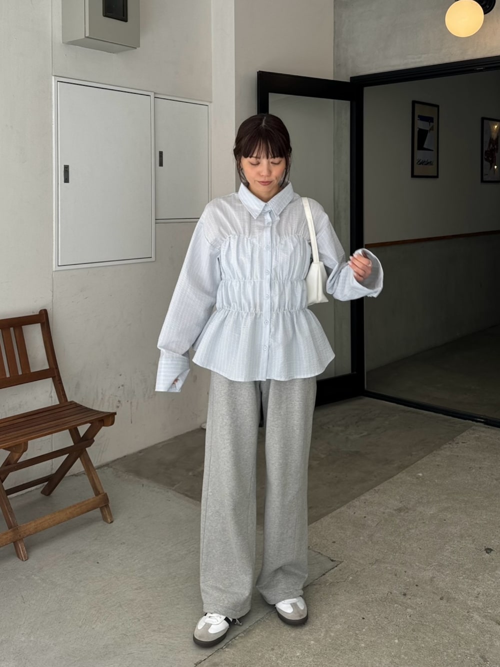 ブルー系のシャツ/ブラウス、グレー系のスウェットパンツ、ホワイト系のハンドバッグを着用したレディースの春コーディネートの2枚目の写真