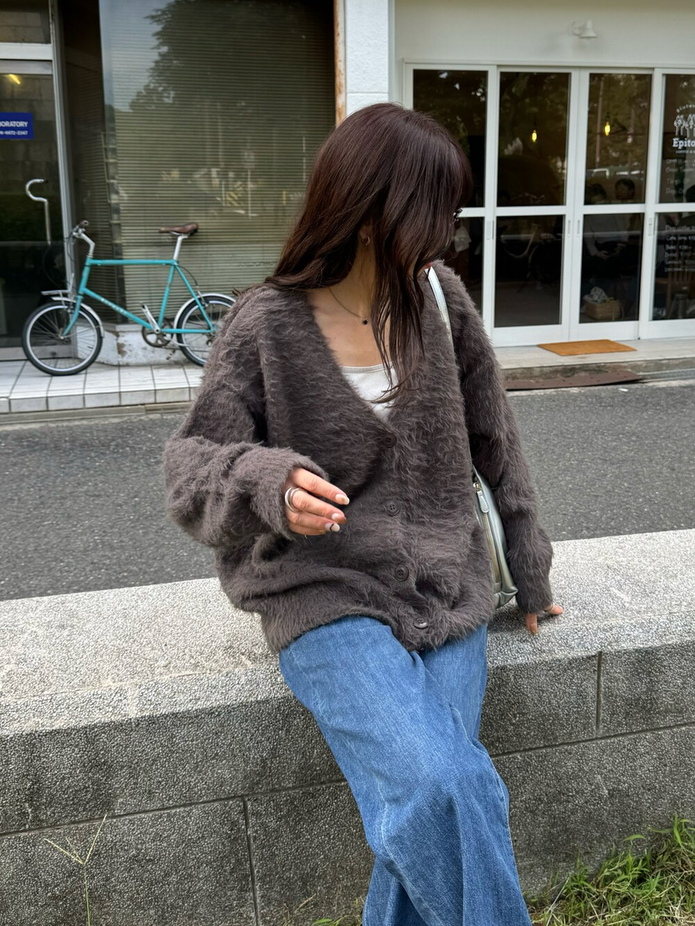 グレー系のカーディガン/ボレロ、ブルー系のデニムパンツ、ベージュ系のスニーカーを着用したレディースの秋コーディネートの3枚目の写真