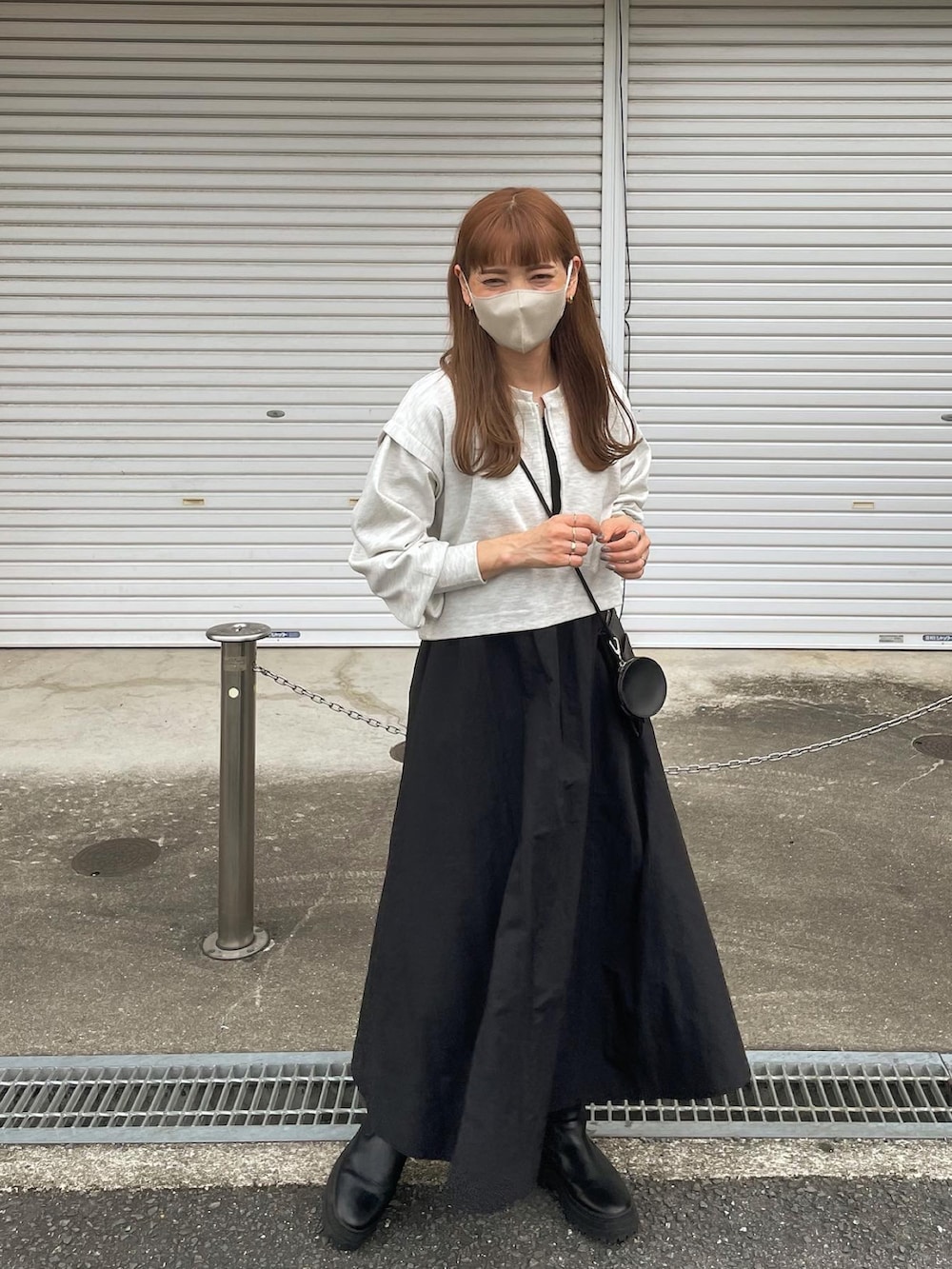 グレー系のワンピース、ブラック系のショルダーバッグ、ブラック系のブーツを着用したレディースの秋コーディネートの3枚目の写真