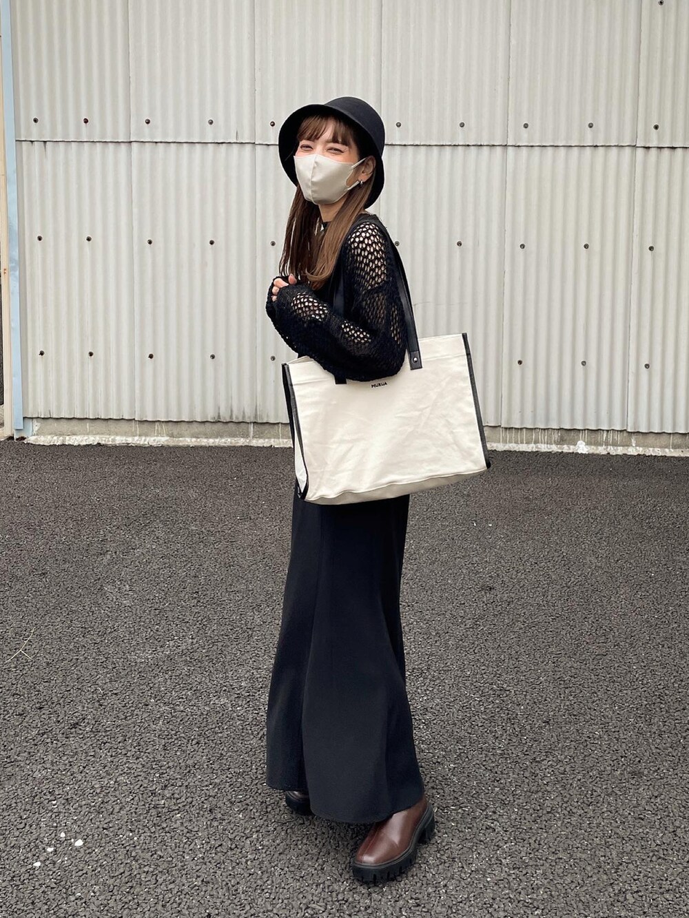 ブラック系のニット/セーター、ホワイト系のトートバッグ、ブラウン系のブーツを着用したレディースの秋コーディネートの3枚目の写真